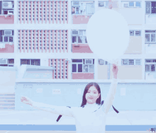 a girl holding a white balloon in front of a building with a sign that says ' a ' on it