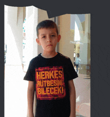 a young boy wearing a black shirt that says herkes rutbesin bilecek