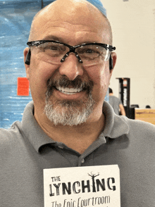 a man wearing glasses and holding a book titled the lynching