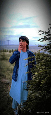 a man smoking a cigarette in a field with the date 28/05/2023 at the bottom