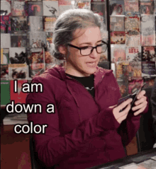 a woman wearing glasses and a maroon jacket says i am down a color while looking at her phone