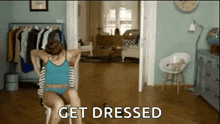 a woman in underwear is sitting on a chair in a living room and getting dressed .