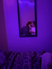 a couple taking a selfie in front of a mirror with purple lights