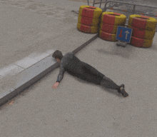 a man is laying on the ground in front of a stack of tires and a sign pointing to the right