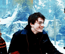 a young man wearing glasses and a black jacket smiles in the snow