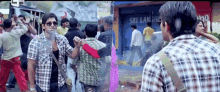 a man in a plaid shirt stands in front of a building that says ' sri lanka ' on it