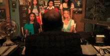 a man sits at a desk in front of a group of girls and a poster that says van lake