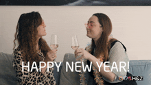 two women sitting on a couch with glasses of wine and the words happy new year written on the bottom