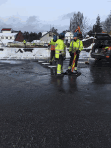 a group of construction workers standing on a wet road