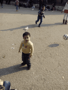 a young boy wearing a yellow shirt that says ' tigger ' on it is playing with a soccer ball