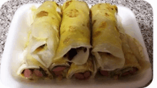 three rolls of food are on a styrofoam tray on a table .