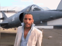 a man in a suit stands in front of a jet with the number 36 on it