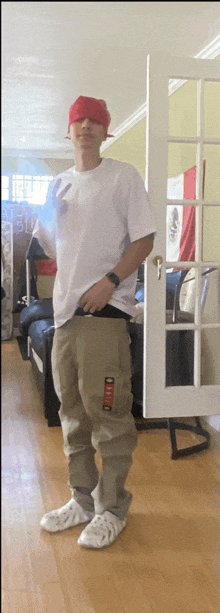 a man in a white shirt and khaki pants is standing in front of a french door