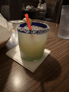 a margarita with a red straw in it sits on a napkin on a table