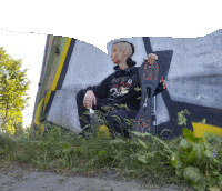 a man wearing headphones is holding a skateboard in front of a wall that has graffiti on it