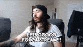 a man with long hair and a beard is sitting in front of a microphone and saying lets goooo forza stream !!!