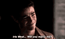 a young man is smiling and asking iris west if he will marry her .