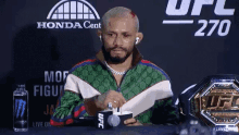 a man is sitting at a table with a ufc championship belt on it .