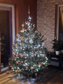 a decorated christmas tree in a living room with a brick wall behind it