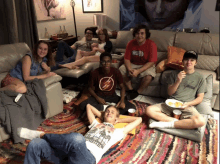 a group of people are sitting on a couch with one wearing a shirt that says the flash on it