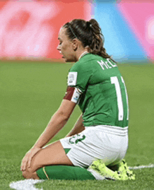 a female soccer player is kneeling down on the field during a game .