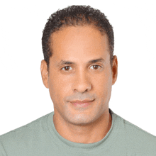 a man in a green shirt looks at the camera with a white background