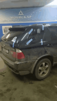 a dirty car is parked in front of a wall that says mobiscap