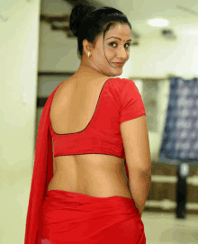 a woman wearing a red blouse and red saree