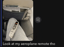 a person is sitting on a plane with a remote control on their lap