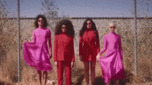 a group of women are standing next to each other in front of a chain link fence wearing red clothes .