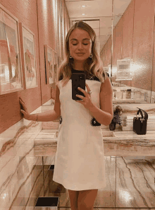 a woman taking a picture of herself in a bathroom mirror