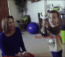 a little boy is holding a trophy in front of a woman with the words red mountains on the bottom