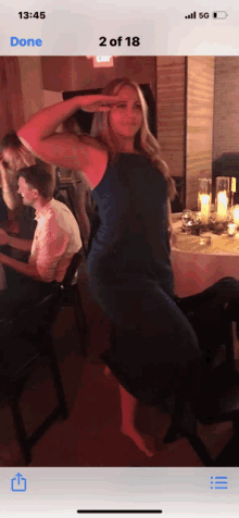 a woman in a blue dress is dancing in front of a table with candles