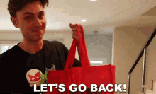 a man holding a red bag with the words let 's go back written on it