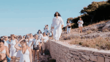 a group of people in white walking down a stone path