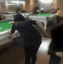 a woman is playing pool in a pool hall while a group of people watch .