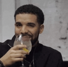 a man with a beard is holding a glass of water with a lemon slice .