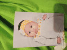 a baby wearing a yellow headband is laying on a green blanket