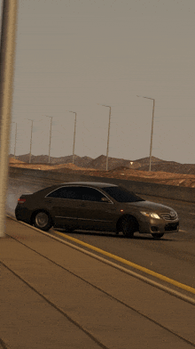 a car is driving down a highway with mountains in the background and a few street lights