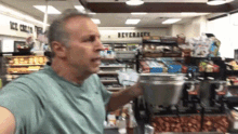 a man in a green shirt is holding a metal container in a store with a sign that says beverages