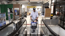 a man pushes a child in a shopping cart on an escalator in front of a store that says chaveiro