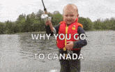 a young boy in a life jacket is holding a fishing rod in front of a body of water .