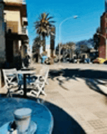 a cup of coffee is sitting on a table in front of a street with palm trees .