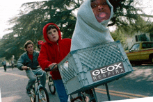 a group of kids are riding bikes down a street with a crate that says geox respira on it