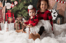 two little girls are posing for a picture in front of a christmas tree and a milk bottle that says milk for santa