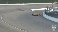 a yellow and red race car is on a track that says indycar on the bottom