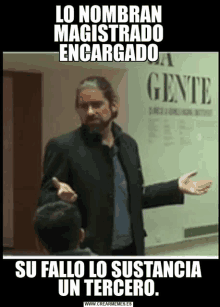 a man with a beard is standing in front of a wall that says gente