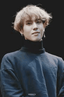 a young man is wearing a black turtleneck sweater and earrings .