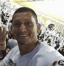 a man in a white shirt is standing in front of a crowd of people at a soccer game .