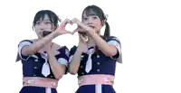 two girls are making a heart shape with their hands and one has a microphone in her mouth